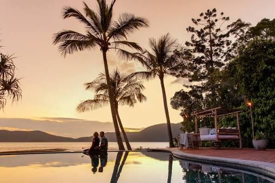 A couple sitting beside an infinity pool at sunset in Australia