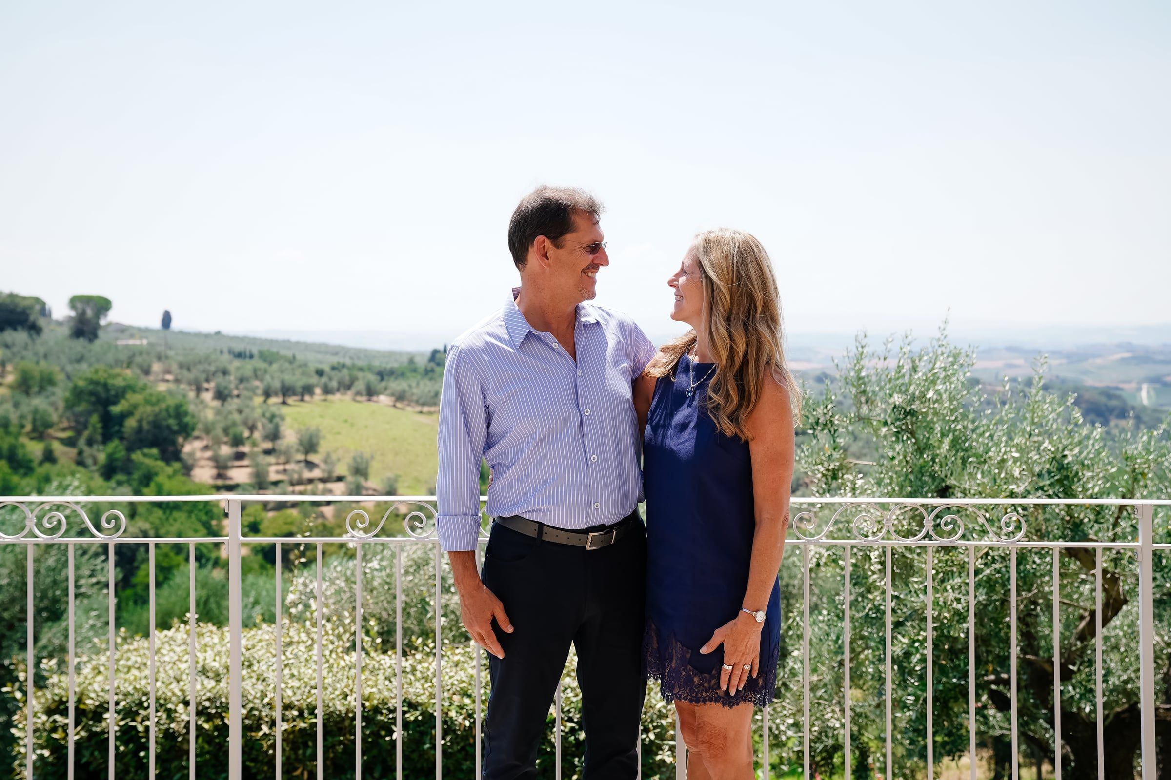 A couple smiling at each other on a terrace above the Italian countryside